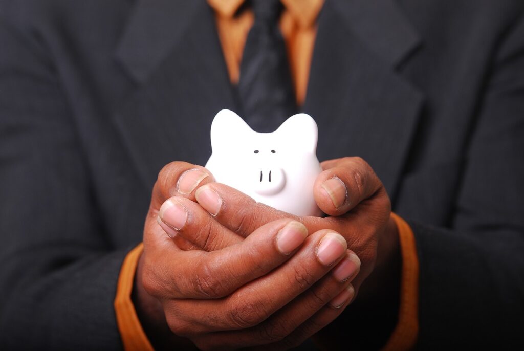 A white piggy bank held in a person's hands